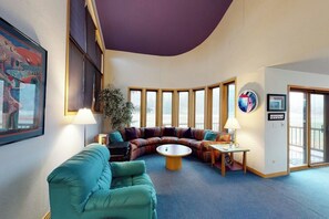 Ein modernes Interieur mit gewölbter Decke, einer Eckcouch, einem runden Couchtisch und großen Fenstern.