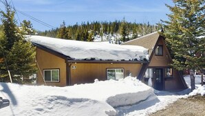 A wooden building with a sloped roof, surrounded by snow and trees. - Cozy mountain-view house with full kitchen, dog-friendly & convenient location (Winter Park)