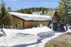 Un bâtiment en bois, doté d’un toit en pente, entouré de neige et d’arbres.