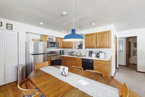 A modern kitchen with wooden cabinets, stainless steel appliances, and a blue pendant light. - Cozy mountain-view house with full kitchen, dog-friendly & convenient location (Winter Park)
