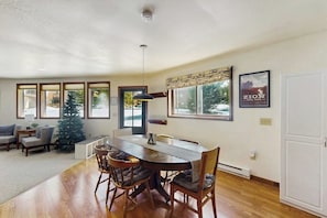 A dining area with a wooden table and chairs, a Christmas tree, and a poster on the wall. - Cozy mountain-view house with full kitchen, dog-friendly & convenient location (Winter Park)
