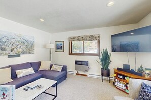 A modern living room with a sofa, coffee table, TV, and artwork. - Cozy mountain-view house with full kitchen, dog-friendly & convenient location (Winter Park)