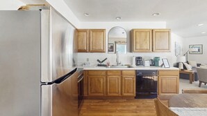 A compact kitchen with wooden cabinets, a stainless steel refrigerator, and a dishwasher. - Cozy mountain-view house with full kitchen, dog-friendly & convenient location (Winter Park)