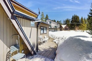 Un bâtiment en bois doté d’une terrasse, de chaises d’extérieur et entouré de neige.