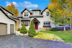 A two-story house with a red door, stone accents, and a well-maintained lawn. - Spacious home w/ private hot tub, modern kitchen, grill & great location (Edwards)