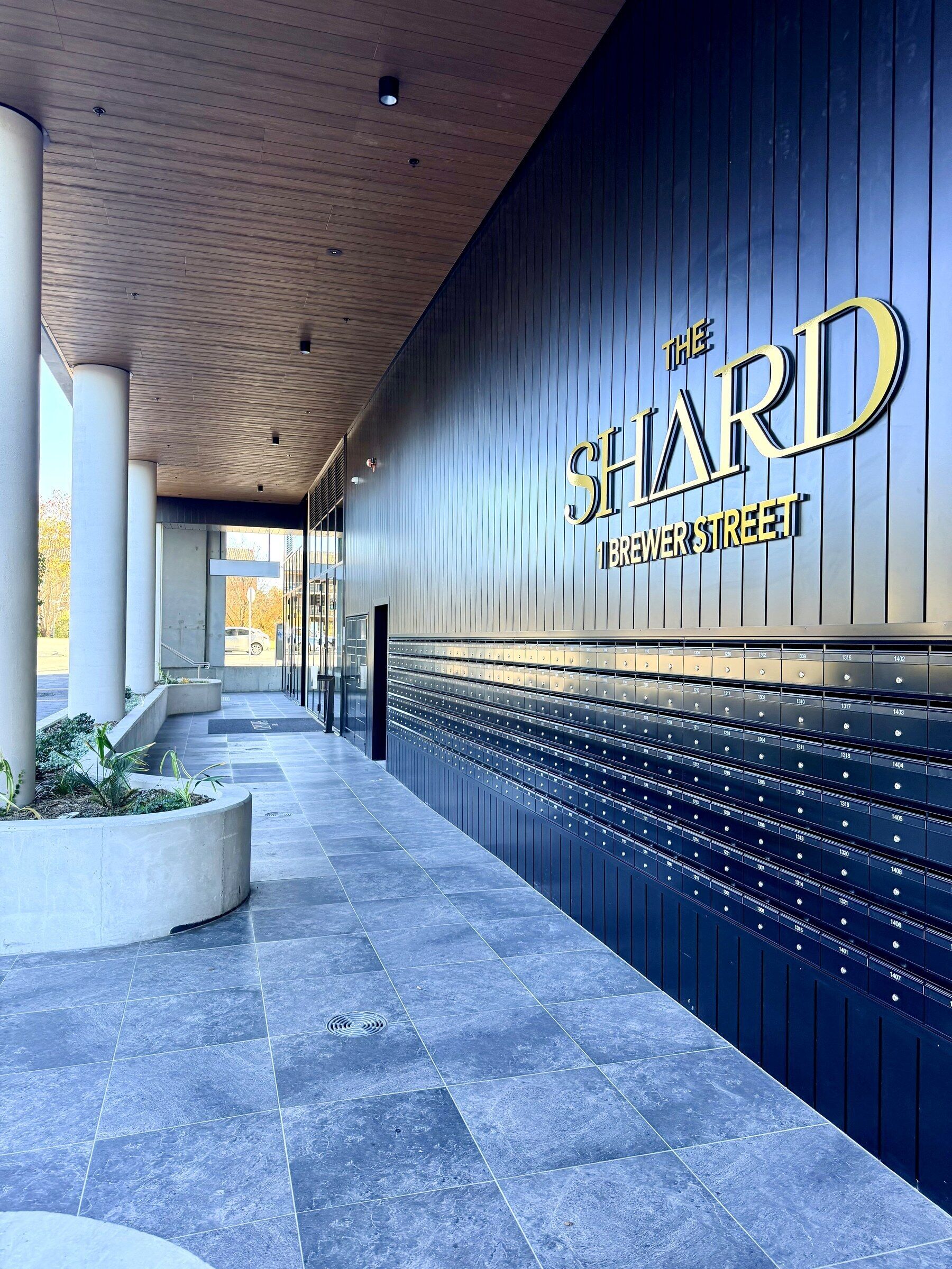 Een modern gevelontwerp met een opvallend bord waarop 'The SHARD' en 'Breezer Street' staat.