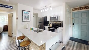 Cocina moderna con una isla grande, electrodomésticos de acero inoxidable y un letrero que indica 'Ski Trails' cerca.