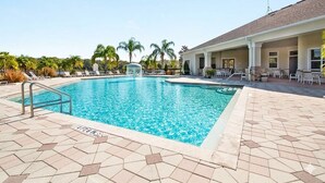 A swimming pool with a water fountain, lounge chairs, and a covered patio area. - Bright & Airy 3-bdrm near attractions w/ gorgeous community pool in Kissimmee (Kissimmee)