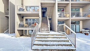 Un edificio de varios pisos con una escalera central que lleva a la entrada, rodeado de nieve.