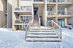 Ein mehrstöckiges Gebäude mit einer zentralen Treppe, die zu einem Eingang führt, umgeben von verschneitem Gelände.