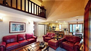 A spacious living room with a high ceiling, a staircase, a dining area, and a kitchen. - Creekside Condo w/ Deck: Short Drive to Skiing, Vail Village & Golf (Vail)