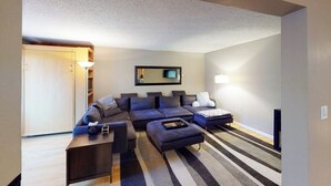 Ein modernes Wohnzimmer mit einer Eckcouch, einem kleinen Tisch und einer Lampe.