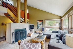 Ein Wohnzimmer mit Kamin, einer Couch, einem Couchtisch und einer Treppe.