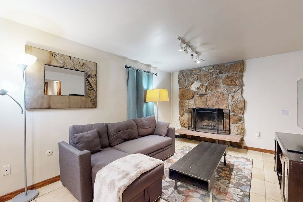Un salon comprenant un canapé, une table basse, une cheminée, une lampe et un téléviseur.