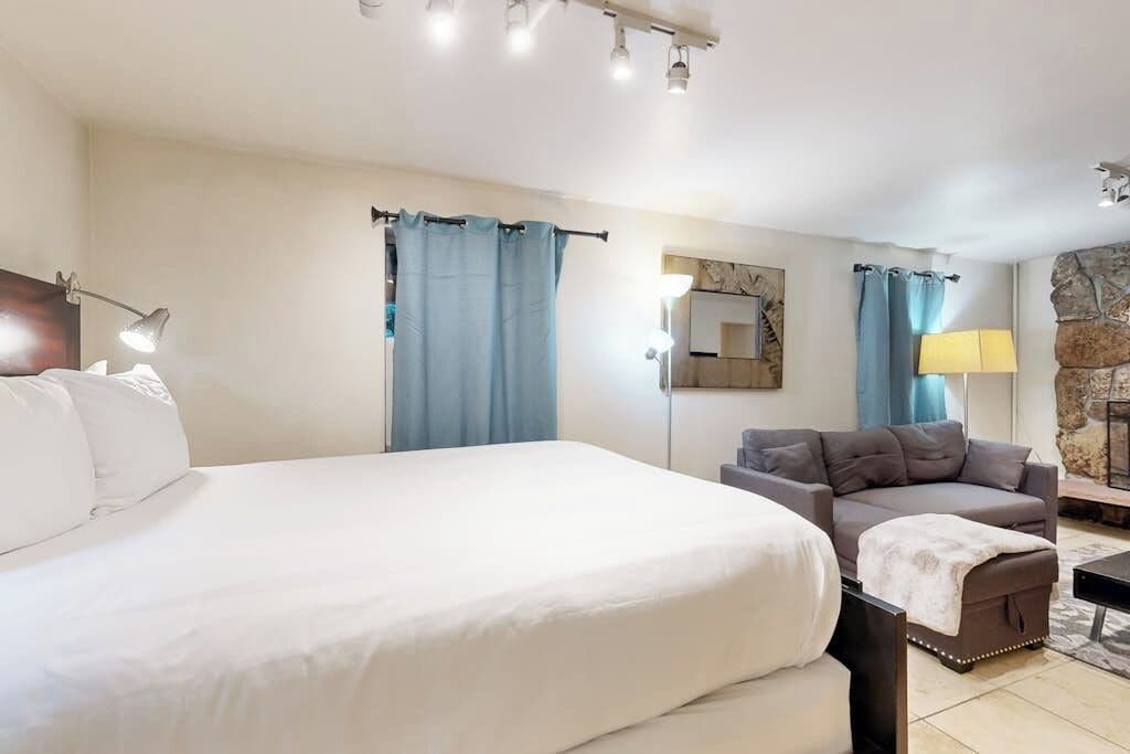 Une chambre d’hôtel avec un grand lit, un canapé, une lampe et un mur décoratif en pierre.