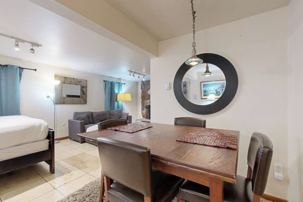 Une pièce comprenant un lit, un canapé, une table à manger avec des chaises, un miroir et une lampe.