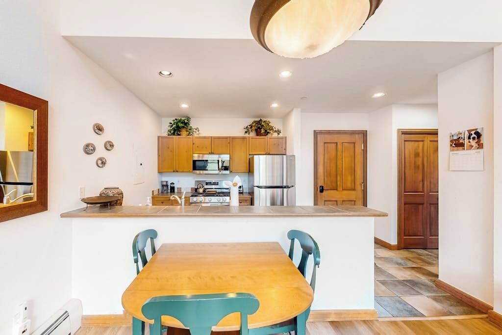 A kitchen with wooden cabinets, a central island, and a dining area with a table and chairs.