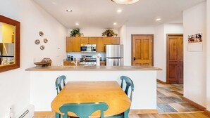 Une cuisine dotée de meubles en bois, d’un îlot central et d’un coin repas avec une table et des chaises.