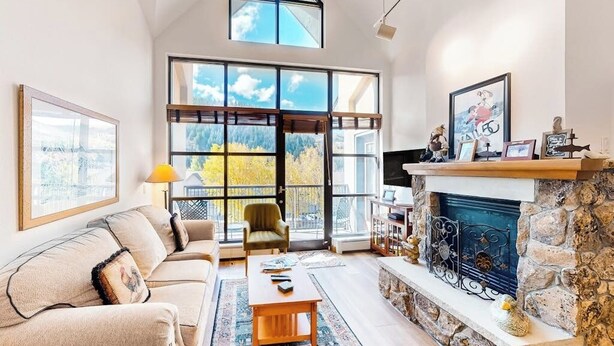 Un salon spacieux avec un haut plafond, de grandes fenêtres, une cheminée et un coin salon confortable.