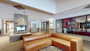 A modern lobby with a stone fireplace, leather sofa, and a TV screen. - Modern condo steps to gondola & lake w/ view & patio - in heart of everything (Avon)