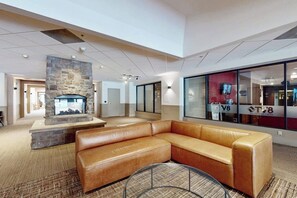 Eine moderne Lobby mit Kamin aus Stein, einer Ledersofa und einem Fernsehbildschirm.