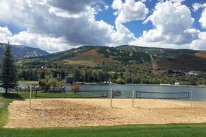Ein Beachvolleyballfeld mit einem See und Bergen im Hintergrund.