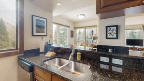 A kitchen with a double sink, wooden cabinets, and a large window. - Chic mtn-view condo near golf & Nordic center with pool, hot tub, game room (Vail)