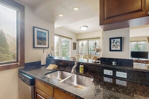 A kitchen with a double sink, wooden cabinets, and a large window. - Chic mtn-view condo near golf & Nordic center with pool, hot tub, game room (Vail)