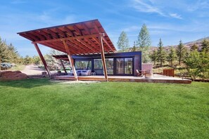 Eine moderne Außenkonstruktion mit Glasfassade, Holzterrasse und Metalldach.
