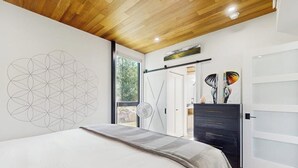 Une chambre à coucher comprenant un lit, une commode, un tableau décoratif et une porte donnant sur un balcon.