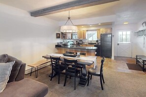 A modern kitchen with a dining area, featuring a central island, wooden cabinets, and a hanging light fixture. - Mtn-view condo with in/out pools, hot tub, fireplace, great views, rec center (Winter Park)