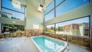 Ein Wellnessbereich mit Whirlpool, großen Fenstern und Blick ins Freie.
