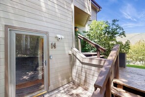 Eine Holzterrasse mit Glastür, einer Treppe und Blick auf die umliegende Landschaft.