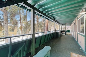 A covered outdoor area with benches, a railing, and a view of trees. - Conveniently located condo w/ shared pool, hot tub, game room, fitness area (Winter Park)