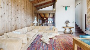 A spacious living area with a large beige sectional sofa, a colorful rug, and a wooden ceiling. - Spacious Mountain Lodge-Style Home with Free WiFi - Nearby Ski Access (Aspen)