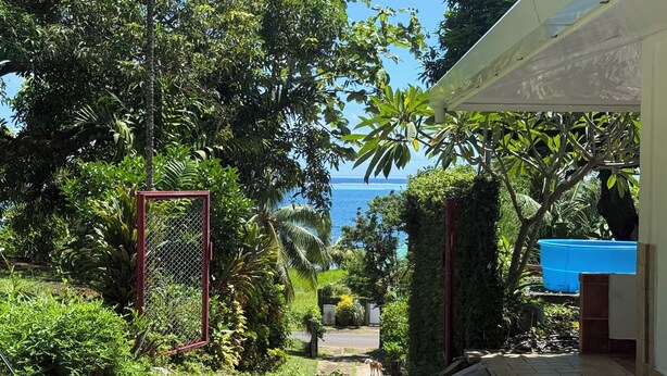 A pathway leading to a house with a view of the sea, surrounded by lush greenery. - Hiro'a - Fare Orotia (Raiatea)
