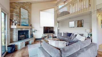 A living room with a fireplace, a television, a sofa, and a balcony.