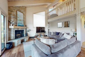 Ein Wohnzimmer mit Kamin, Fernseher, Sofa und Balkon.