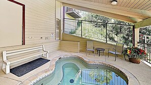Un'area esterna coperta con piscina, una panchina, sedie e una ringhiera.