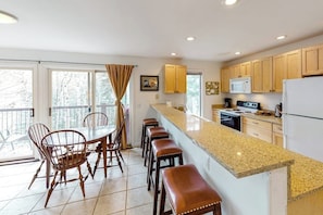 A kitchen with a granite countertop, wooden cabinets, a microwave, stove, and a refrigerator.