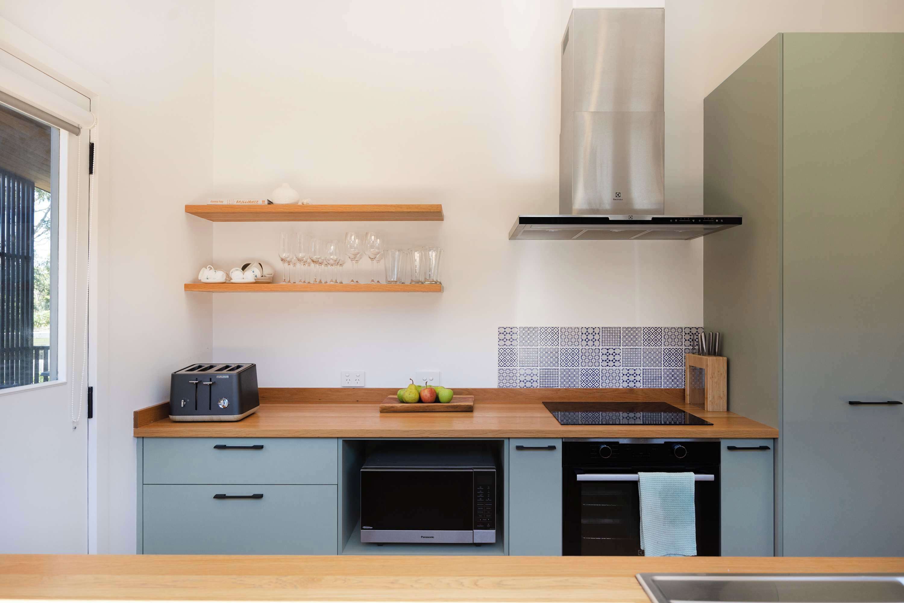 A modern kitchen with a toaster, microwave, oven, and a stainless steel range hood.
