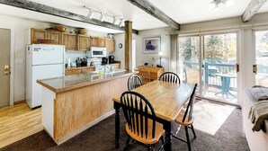 Una cucina con mobili in legno, un frigorifero bianco, un forno a microonde e un tavolo da pranzo in legno con sedie.