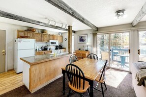 Eine Küche mit Holzausbau, einem weißen Kühlschrank, einer Mikrowelle und einem Esstisch mit Stühlen.