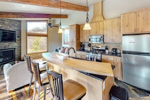 A kitchen with wooden cabinets, a central island, a stove, and a refrigerator.