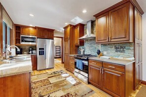 A modern kitchen with wooden cabinets, stainless steel appliances, and a patterned rug. - Mountain Gem Walking Distance From Slopes w/Shared Pool & Hot Tubs, Free WiFi (Snowmass)