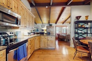 A kitchen with wooden cabinets, a stainless steel stove, and a dining area with wicker chairs.
