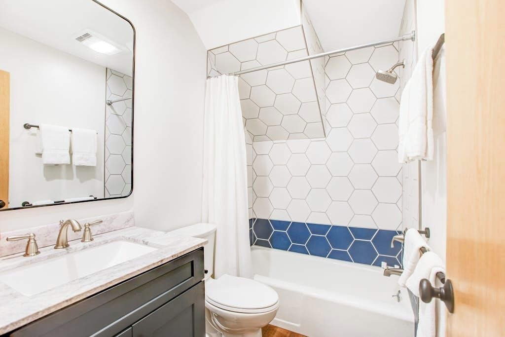 Een badkamer met een wit wastafel, toilet, bad en douche met honingraat tegels.