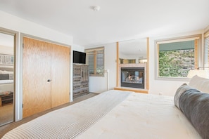 A bedroom with a bed, a fireplace, a closet, and a window with blinds.