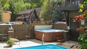 Una piscina con idromassaggio, un pontile in legno e vista su una casa e una foresta.