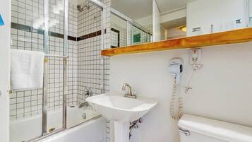 A bathroom with a bathtub, a sink, a hairdryer, and a toilet.